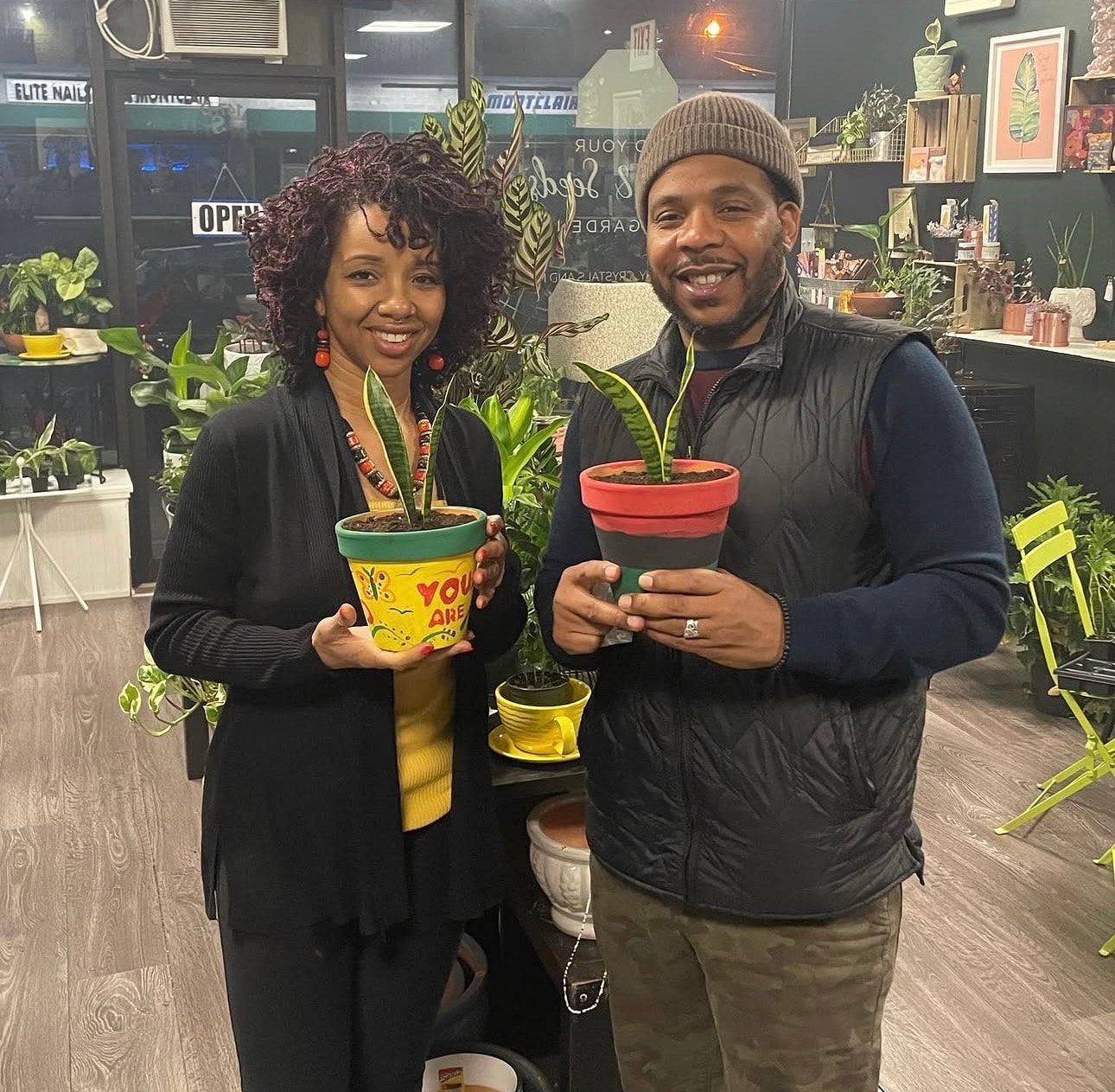 Couple holding their painted pots with plants inside the Mind Your Beads & Seeds shop