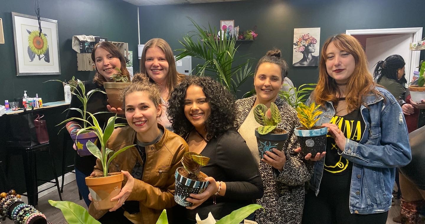 Group of six women holding their painted pots and plants at workshop
