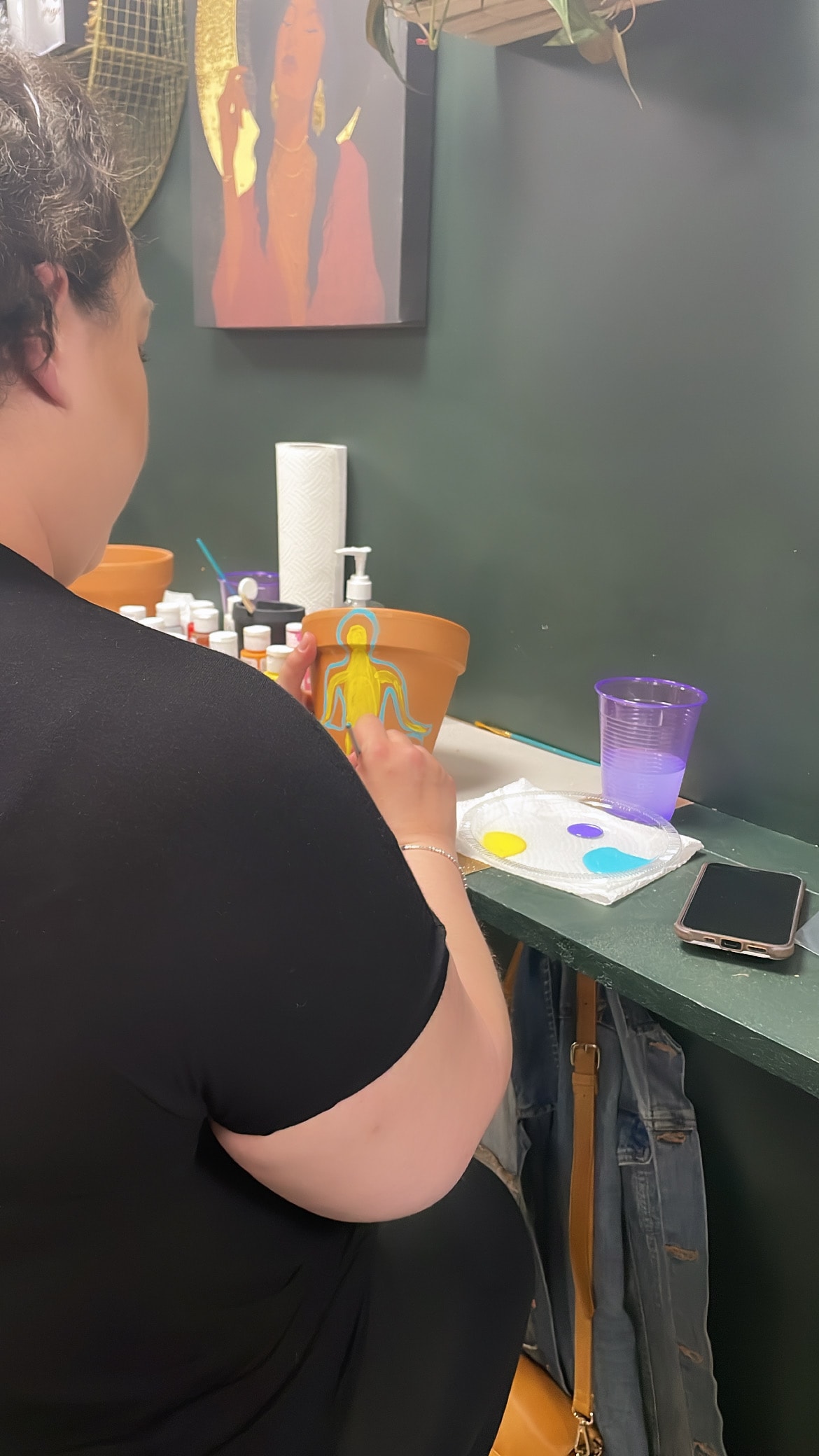 Workshop participant painting a terracotta pot with a figure design